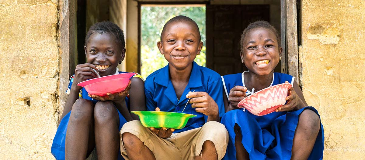 Munjama Toma (left ) enjoys her school meals with friends Mohamed Macfoy and Munjama Kamara