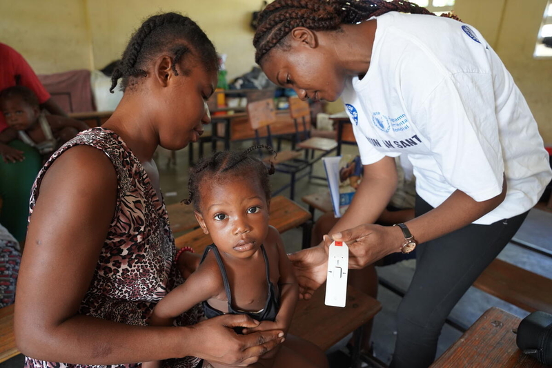 Measuring mid upper arm circumference (MUAC) of a child with moderate acute malnutrition at an IDP site in Joseph Claude Bernard School in Ouest Department, Haiti. (C) WFP/Tanya Birkbeck  