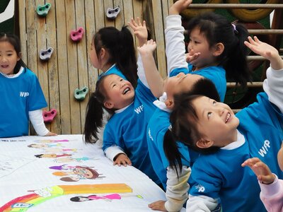 Schoolchildren in WFP sweatshirts reaching upwards, in Xiangxi, Hunan Province of China 