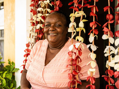 A Dominican woman laughing at camera in front of her house