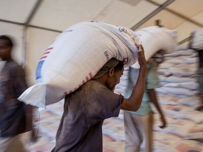 Men carrying bags of food to a warehouse