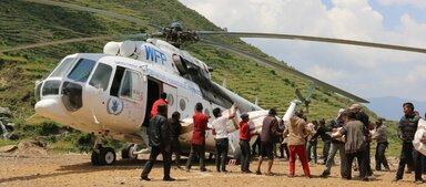 WFP’s forward operating relief hub in Deurali, the UNHAS helicopter offloads relief supplies at a distribution point in Kerauja VDC in Gorkha District in Nepal. The villagers go to the landing area to help offload the tents and High Energy Biscuits for distribution.