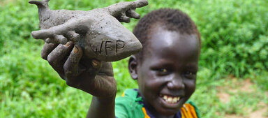 A child holding a plane made from soil