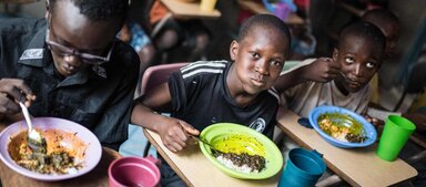 Orphans whose parents died during the Ebola outbreak in Sierra Leone eat lunch made with WFP-provided food at Variety Children and Family Services in Freetown, Sierra Leone. Photo: WFP/Jordan Sissons