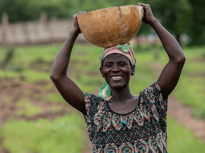 An outgrower of Fonio cereal in the Upper East Region, carrying a bowl of her harvest.