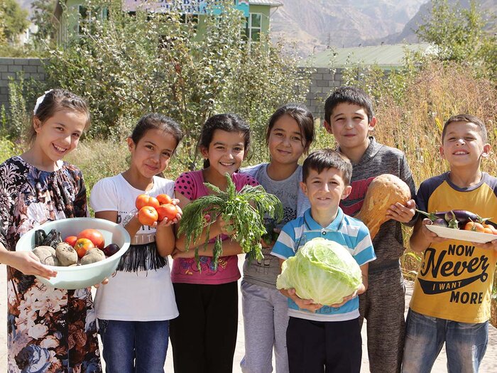 Group of children holding freshly harvested vegetables