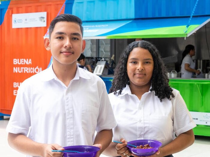 Adolescent boy and girl holding bowls of food