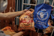 A plastic bag containing bread next to a WFP flag with Arabic font