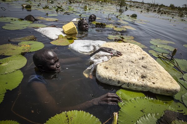 (C)Gabriela VIVACQUA. Meer Koch, 41, displaced within Rubkona county in Bentiu of South Sudan because of flooding, shows WFP the depth of the floodwaters she must wade through in search for water lilies to feed her family. WFP is distributing emergency food assistance as well as livelihoods support to flood-affected populations across 8 of the country’s 10 states.