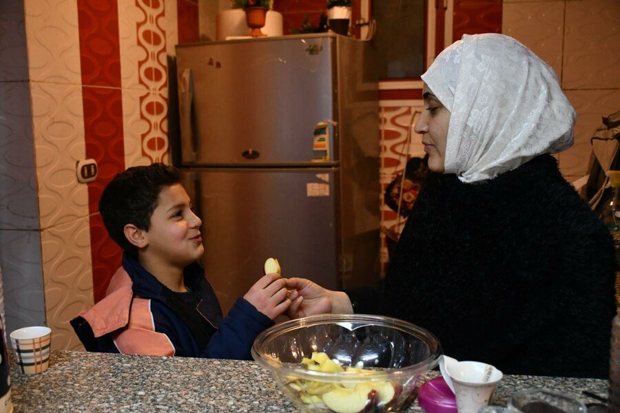 Shady shares an apple with his mother Nour