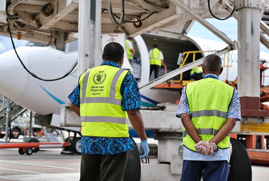 Two men watching cargo being unloaded from a plane