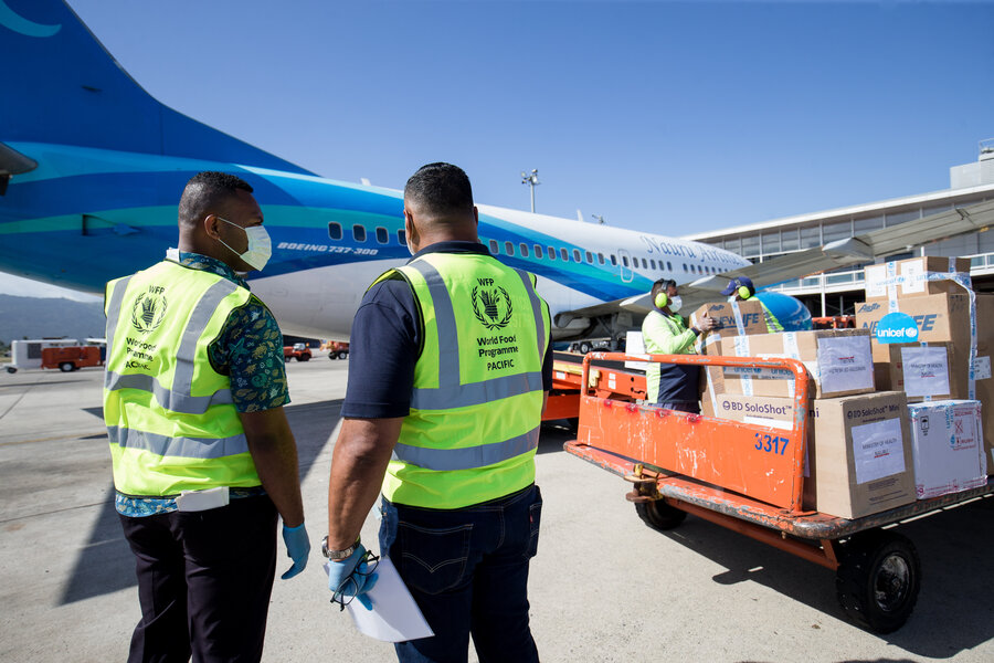 Two people looking at cargo next to plane