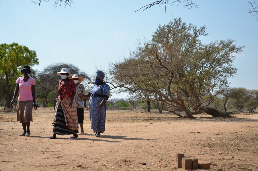 A group of women walk across a brown field.