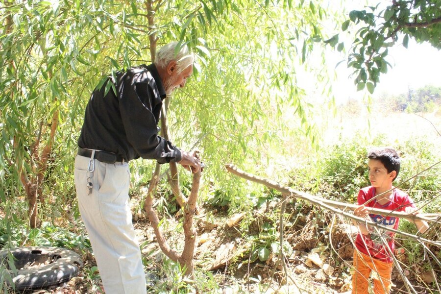 Hasan passes on his experience in planting to his grandson. Photo: WFP/Dana Houalla