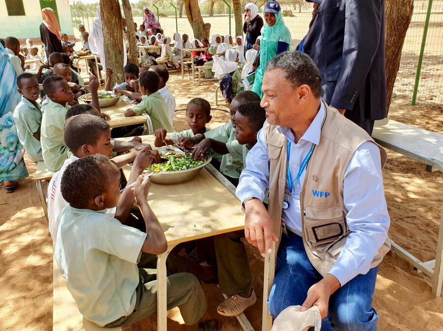 WFP's Hameed Nuru with students in Darfur, Sudan, as they enjoyed a meal cooked with ingredients from their school garden. The visit took place when Nuru was WFP Sudan Country Director. Photo: WFP Sudan 