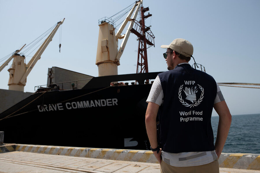 Rear view of a WFP staffer in branded top standing in front of docked ship