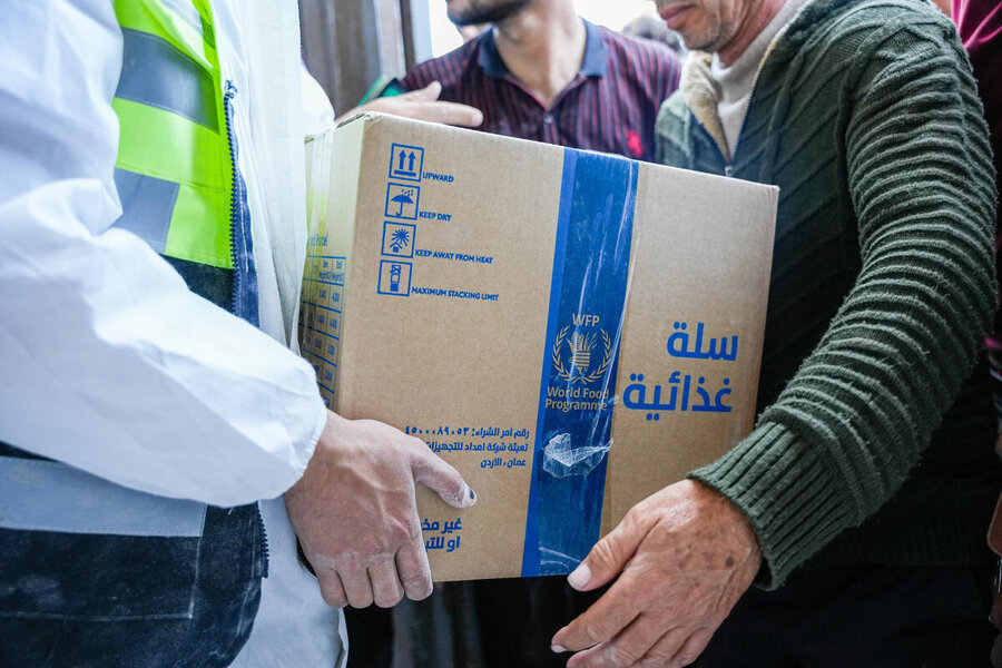 A man handing another man a WFP-branded box of food