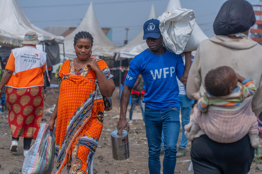 WFP staffer carrying supplies in a camp