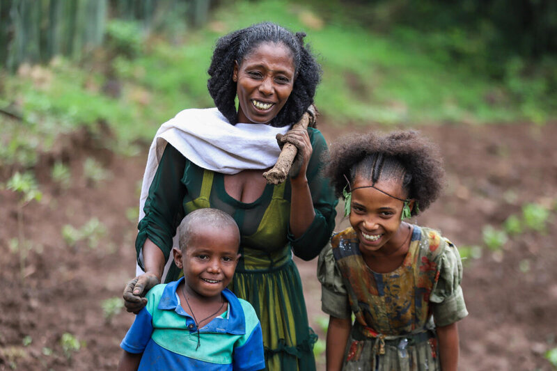 Ethiopia woman with her son and daughter smile as they walk to the fields