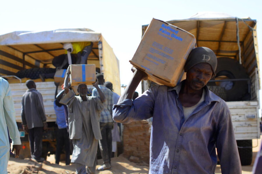 A man carrying away a box of WFP food on his shoulder, at a food distribution