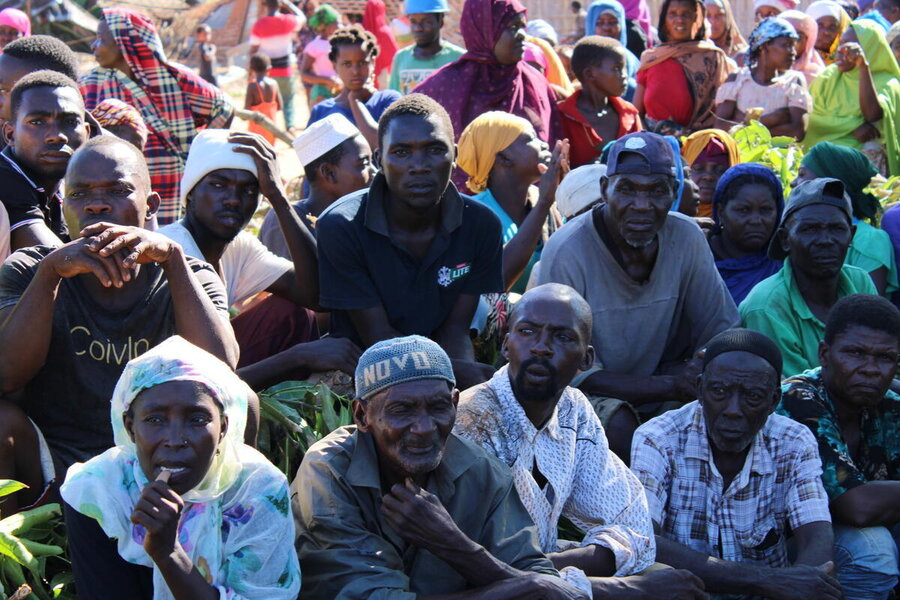 A group of men and women kneeling as they wait in line