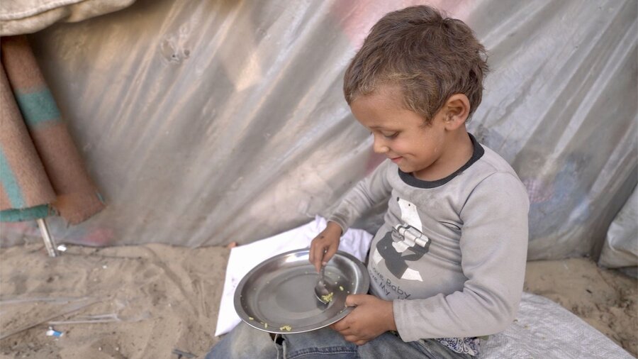 A small boy scoops up the last rice grains in his bowl. Hunger is soaring in Gaza and the WFP food allowed to enter is limited. WFP/Jonathan Dumont