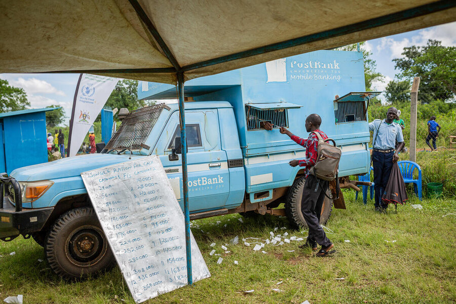 A blue van is seen from under a gazebo, a man is reaching towards an hatch on its side