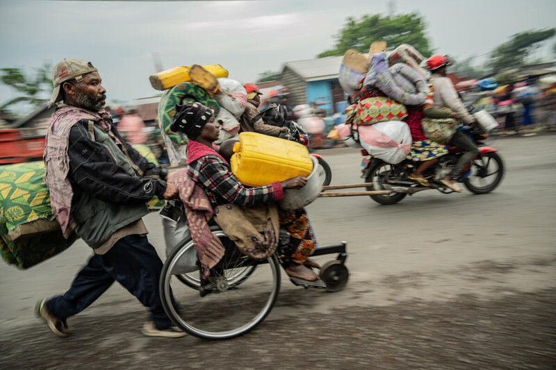 Man pushes wheelchair laden with belongings