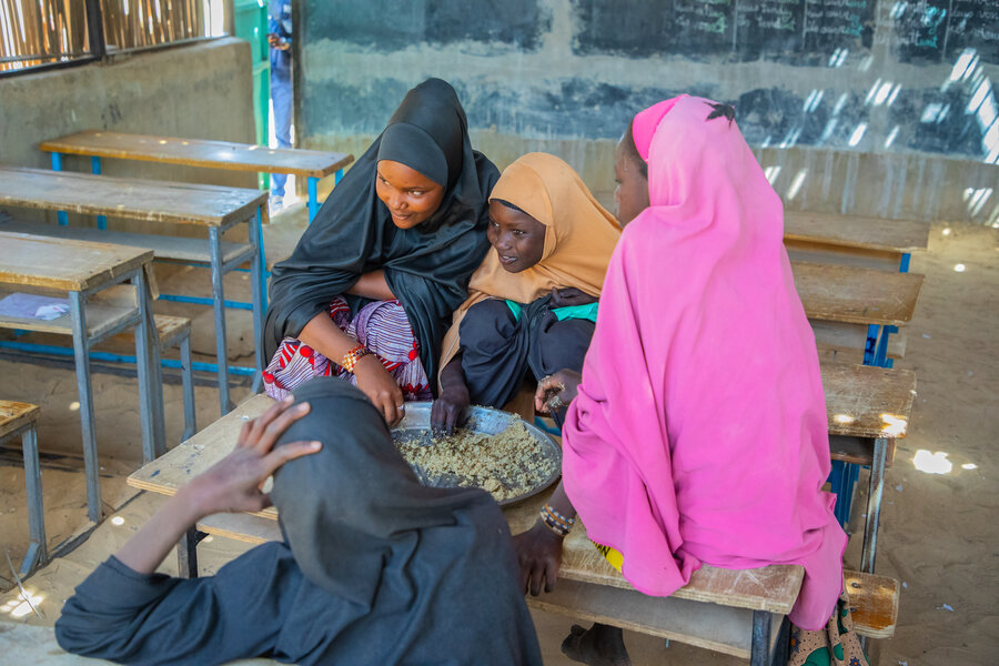 Salamatou Mahamadou (L) eats a WFP-supported school meal with friends. The food has greatly boosted attendance, her school's headmaster says. WFP/Amadou Dansalaou