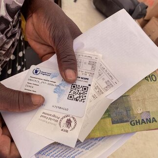 A Burkinabe asylum seeker displaying cash received and a SCOPE Card at Tarikom resettlement center, Upper East Region