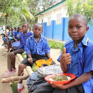 School children are having their meals in a garden