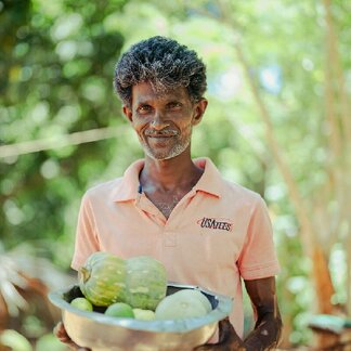 Shantha, farmer from Thanamalwila, Monaragala district holding a bowl of vegetables supported by the WFP Sri Lanka resilience building “R5n” Project.
