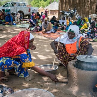 two women are cooking food in a big pot