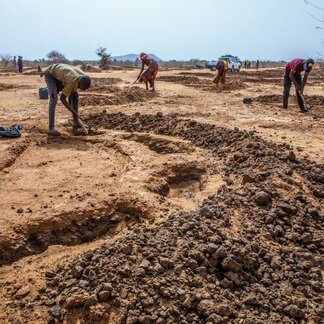 People digging "half moons" in land to collect and retain water.