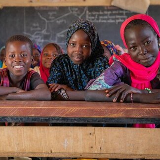 Three children facing camera at a school desk