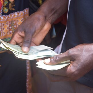 A beneficiary of a joint social protection project counting the cash received under the cash transfer component led by WFP. Photo:  WFP/Charlotte Alves